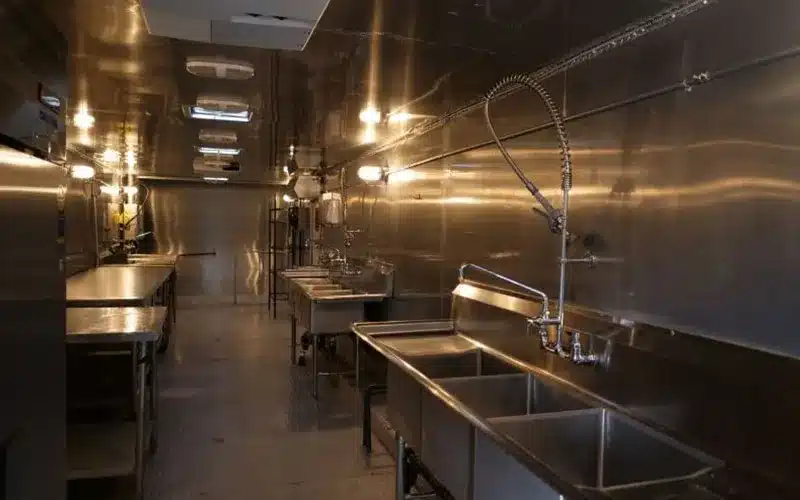 Stainless steel preparation sinks and worktables inside a mobile commercial kitchen